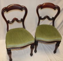 A pair of Victorian carved mahogany balloon-back dining chairs with upholstered seats on turned