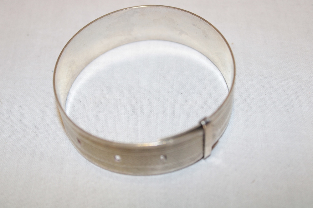 A silver circular bangle with engine turned decoration,