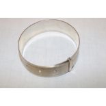 A silver circular bangle with engine turned decoration,