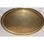 A large Middle Eastern brass oval tray engraved all over with numerous figures,