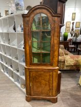 A walnut Queen Anne style corner cabinet, with arched top, glass panels revealing a painted