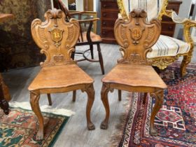 A pair of late Victorian oak heraldic shield back hall chairs, 84cm x 45cm wide
