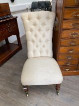 A Victorian button back nursing chair with oak legs to castors, 96cm tall x 50cm wide