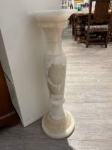 A carved onyx pedestal 82.5cm tall