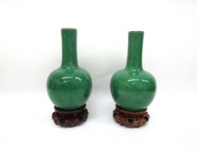 A pair of Chinese apple-green crackle-glazed bottle vases on carved wooden stands, label to inside