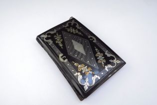 A 19th Century aide memoire, black lacquered with silver and gold inlay of scrolls and floral swags,
