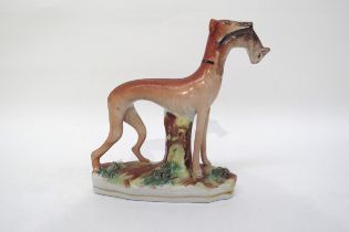 A 19th century standing Staffordshire greyhound with rabbit in mouth, 15cm tall