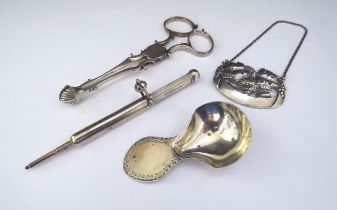 A silver decanter label grape and vine detail, a silver caddy spoon, silver sugar nips and a