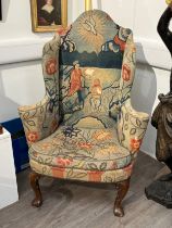 An early to mid 18th century wingback armchair with holy needlepoint upholstery, well worn, thread