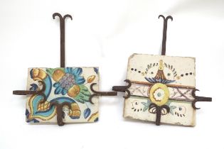 Two 18th Century Faience tiles in wrought iron holders, 37cm x 28cm