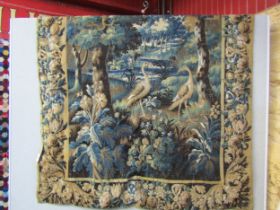 An handwoven wall hanging tapestry featuring a woodland scene with foliage and stylised birds