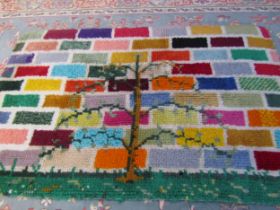 A shag pile style small rug with a bright coloured brick pattern with central tree design, 66cm x