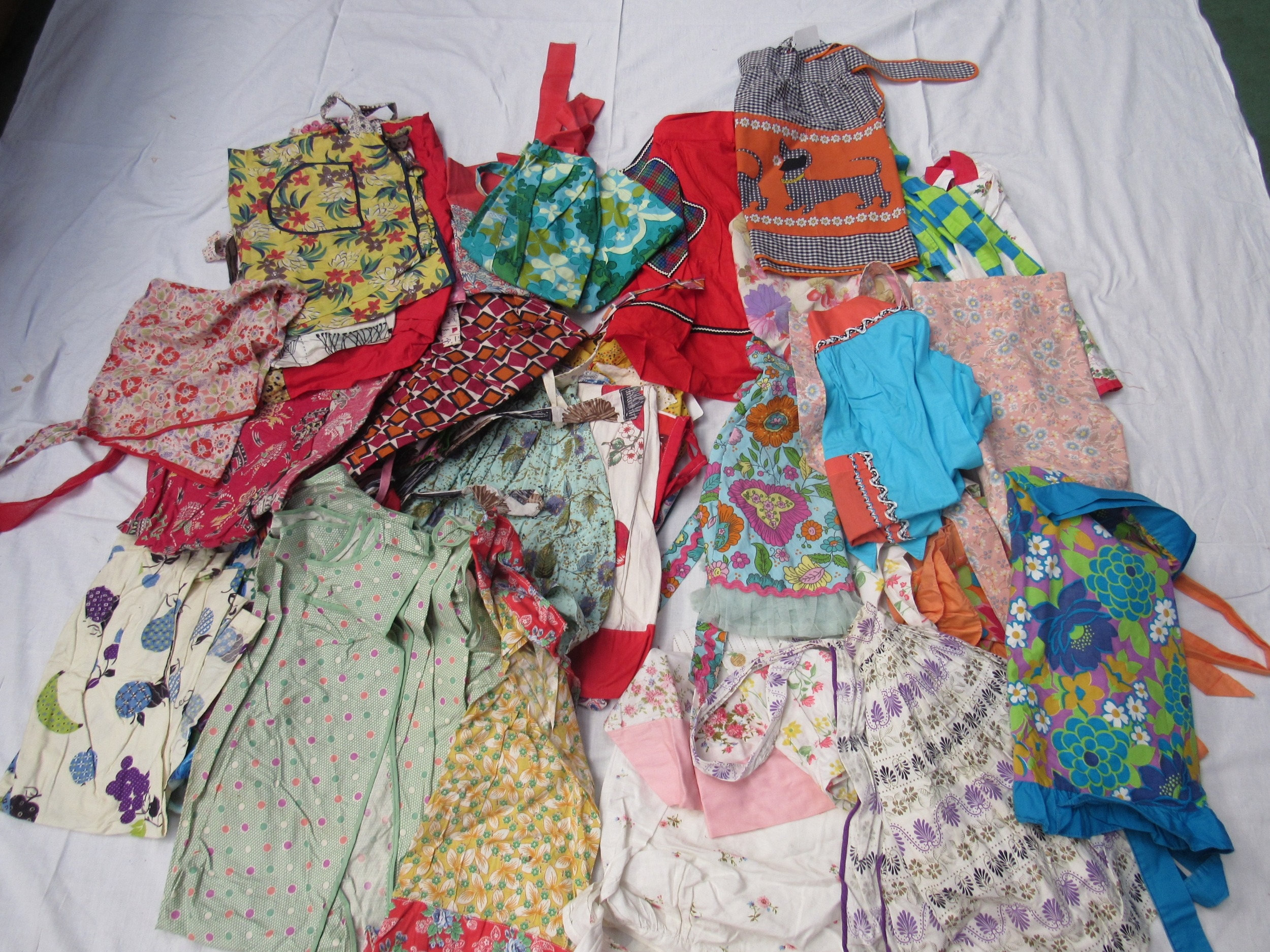 Forty approx colourful printed cotton 1930's - 1960's mainly waist aprons of various design