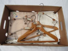 A box containing vintage table linens, huckaback towels and five vintage wooden coat hangers bearing