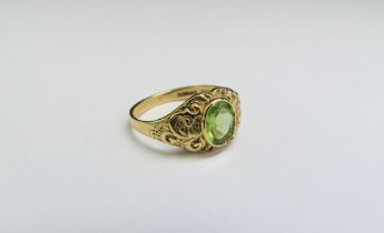 A 9ct gold ring set with an oval peridot in ornate scroll mount. Size I, 1.9g