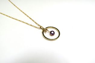 A gold chain, unmarked, 43cm long hung with an amethyst and pearl pendant in circular frame, stamped