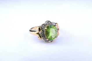 A 9ct gold peridot and diamond ring, the central oval peridot framed by diamond chips. Size N/O, 3.