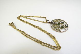 A gold circular pendant with four green droplets stamped 9ct hung on a gold chain stamped 15ct, 40cm