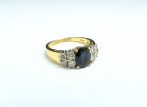 An 18ct gold ring with oval sapphire flanked by four diamonds. Size P, 5.6g