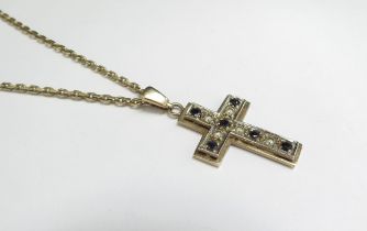 A 9ct gold cross pendant set with sapphires and clear stones hung on a gold chain stamped 9k, 61cm