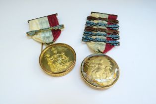 Two silver gilt Masonic medals in glass capsules one with a 15ct gold mount the other 9ct gold, on