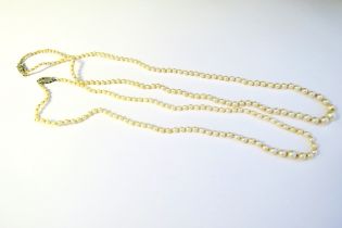 Two single strand pearl necklaces each with a diamond set clasp