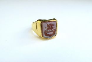A carved seal ring depicting shield crest, stamped 18ct. Size K, 6.1g