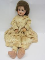 An early 20th Century Schoneau & Hoffmeister bisque head girl doll with brown wig, striated blue