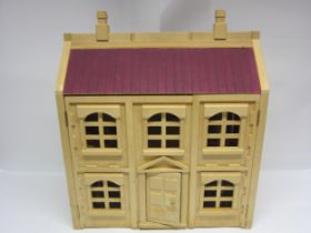 A two storey wooden dolls house with assorted wooden furniture
