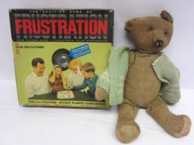 A careworn mid 20th Century straw filled teddy bear with glass eyes and a vintage Frustration