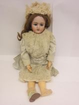 An early 20th Century German bisque head doll with mousey brown wig, striated blue glass sleepy