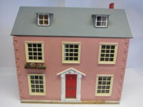 A front opening two storey dolls house with attic rooms above, containing assorted furniture and
