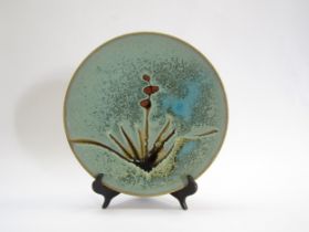A Mashiko Pottery plate with turquoise glaze ground and painted grass and seed head design. No
