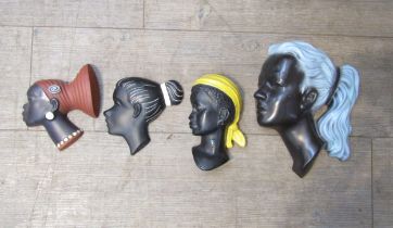 Four painted female head wall plaques in plaster and ceramic, various designs. Largest 26cm high