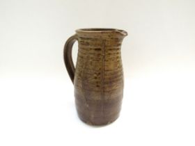 A studio pottery jug in the Leach tradition, incised detail in mottled brown glaze. Incised mark