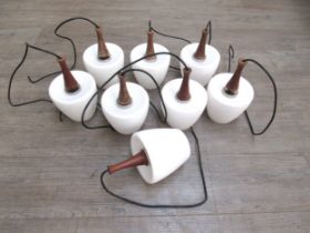 A set of eight Mid Century ceiling pendant lights in teak with white glass shades, each measures