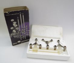 A boxed Nagel chromed metal set of three candle holders with a selection of taper candles.