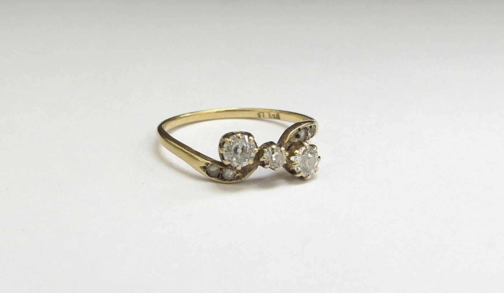 A three stone diamond crossover ring, 0.40ct approx total, stamped 18ct. Size O/P, 1.6g