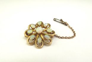 A gold flower form brooch stamped 15ct set with nine opals, 2.5cm diameter, 5.1g