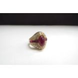 An 18ct gold ring centrally set with a cabochon ruby flanked by a row of square cut rubies all