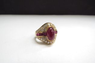 An 18ct gold ring centrally set with a cabochon ruby flanked by a row of square cut rubies all