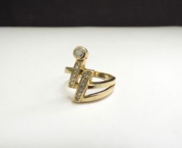A gold ring with two lines of vertical diamonds one terminating with a round cut diamond, stamped