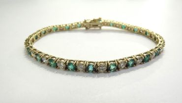 An emerald and diamond line bracelet all in four claw mounts, having 22 alternate set emeralds (3.