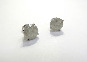 A pair of diamond stud earrings in four claw mount, 3ct approx each stud, cloudy, with all over