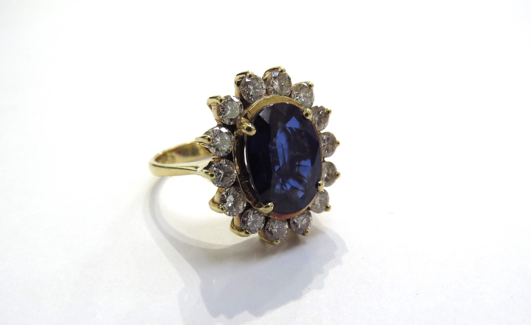 A sapphire and diamond cluster ring the central oval sapphire 11.5mm x 8.5mm, 3.47ct approx set in
