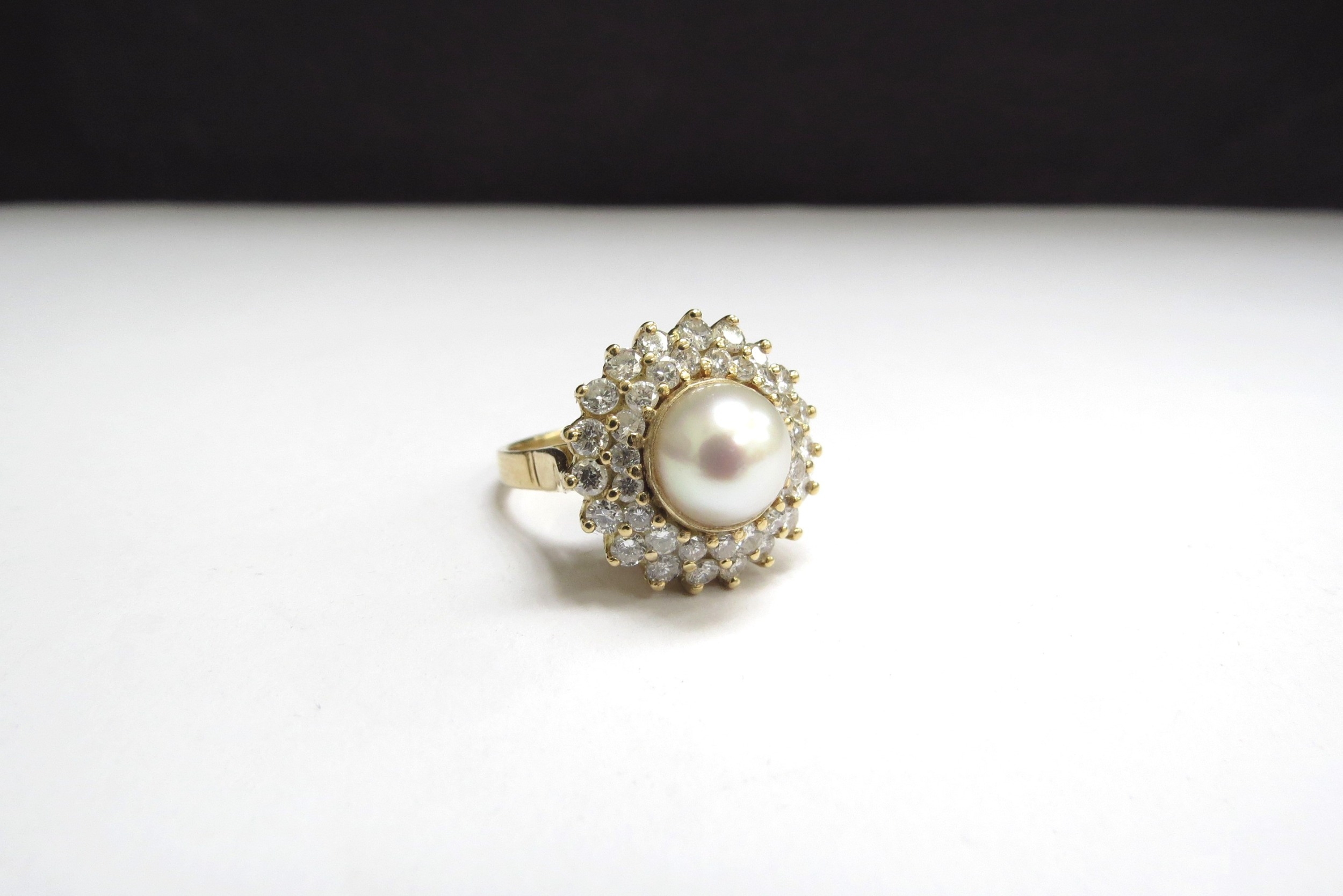 An 18ct gold pearl and diamond ring, the centre pearl 9mm framed by two rows of brilliant cut