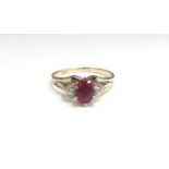 A gold ruby and diamond ring, the centre oval ruby flanked by diamonds, stamped 9ct. Size S, 3.2g
