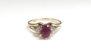 A gold ruby and diamond ring, the centre oval ruby flanked by diamonds, stamped 9ct. Size S, 3.2g