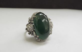A large oval cabochon jade and diamond ring, the jade 20mm x 12mm framed by baguette and round cut