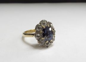 An 18ct gold sapphire and diamond ring the central oval sapphire 8mm x 6mm framed by eight rose